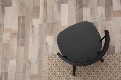 Stylish comfortable black chair on floor, top view. Space for text