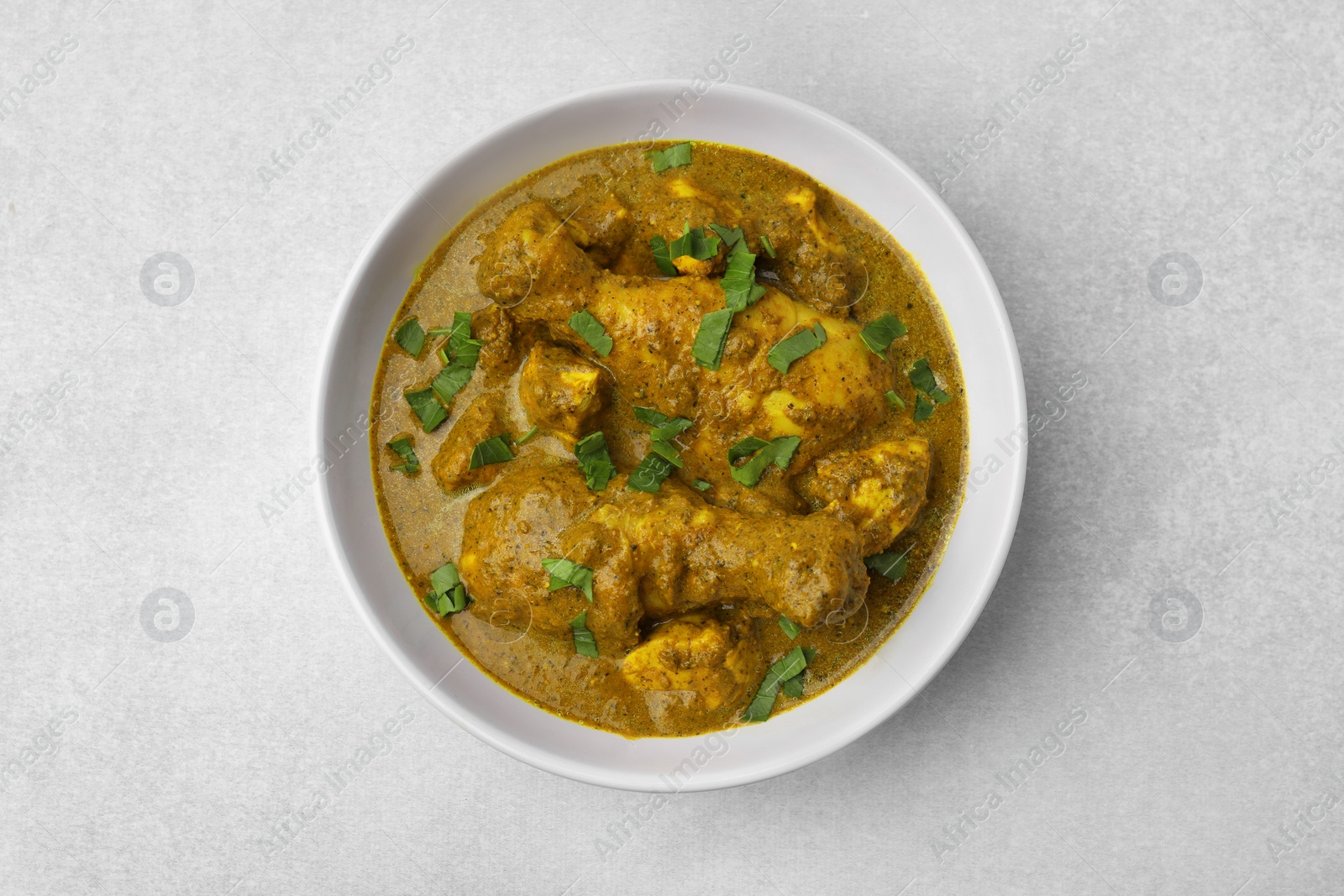 Photo of Delicious chicken with curry sauce on white table, top view