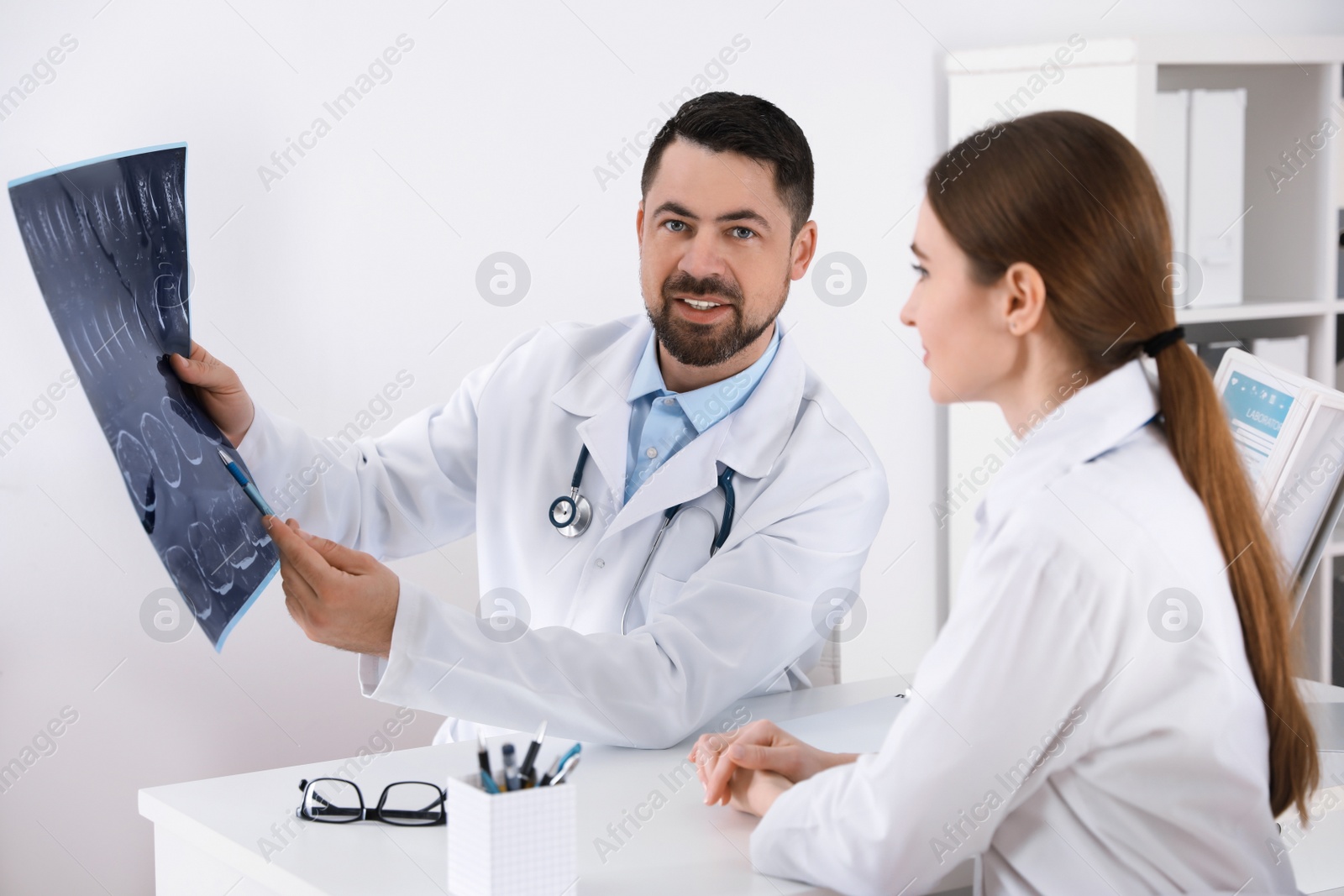 Photo of Orthopedists examining X-ray picture at desk in clinic