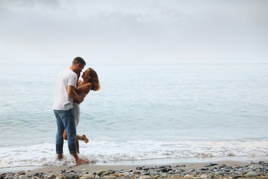 Happy young couple on beach near sea. Space for text