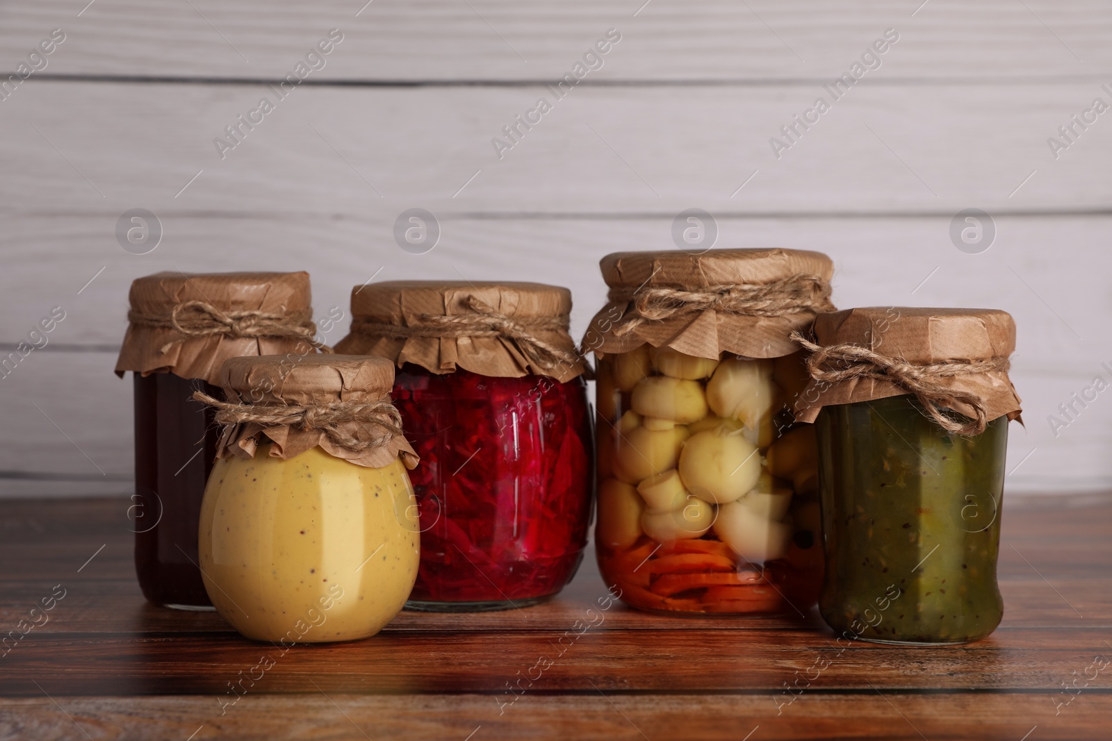 Photo of Many jars with different preserved ingredients on wooden table