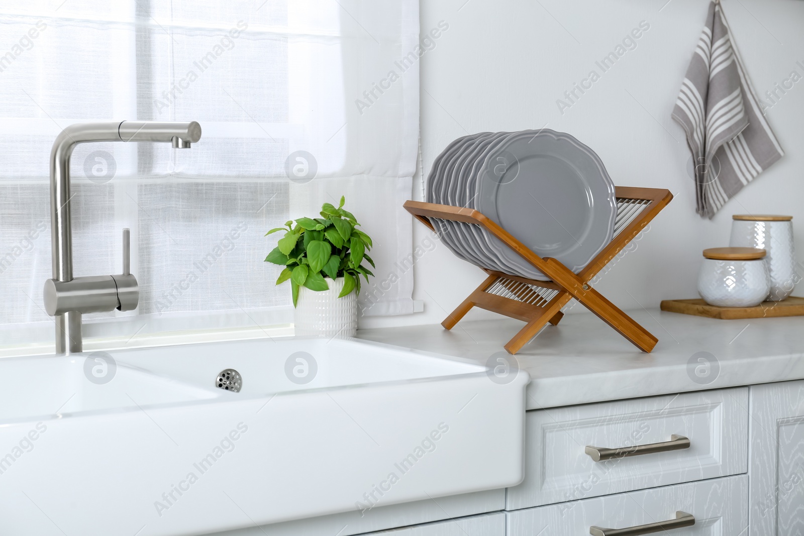 Photo of Wooden holder with grey plates on countertop near sink in kitchen