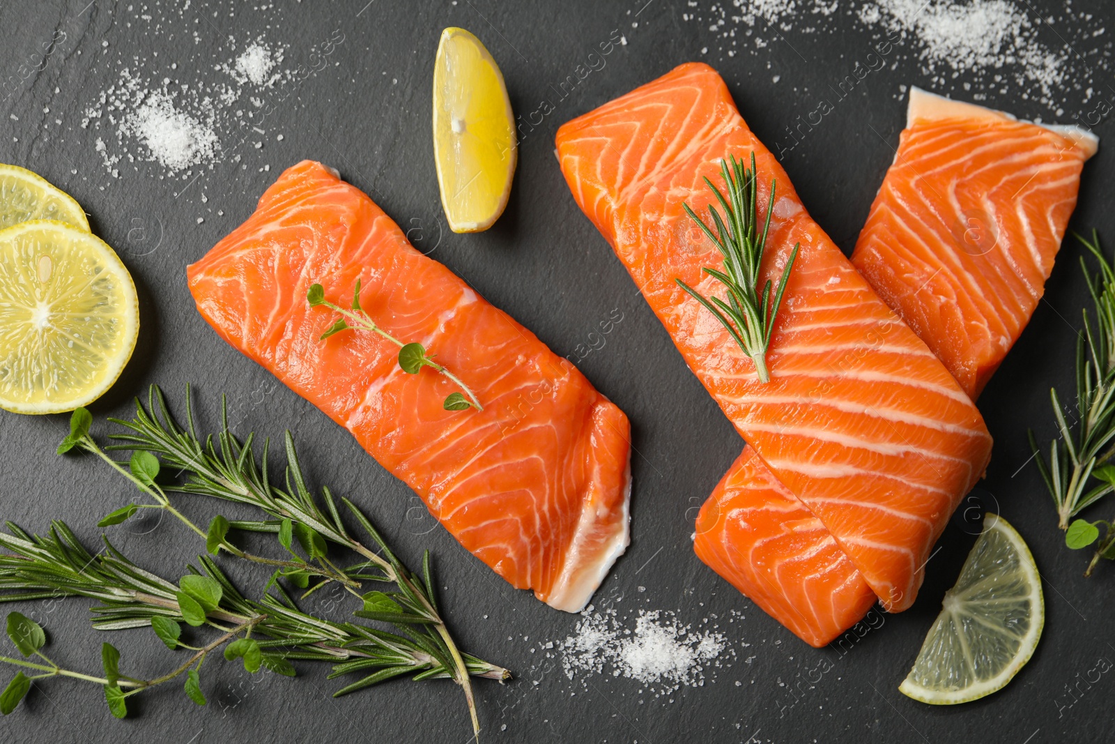 Photo of Fresh salmon and ingredients for marinade on black table, flat lay