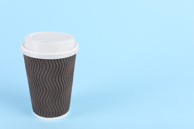 Photo of Brown paper cup with plastic lid on light blue background, space for text. Coffee to go