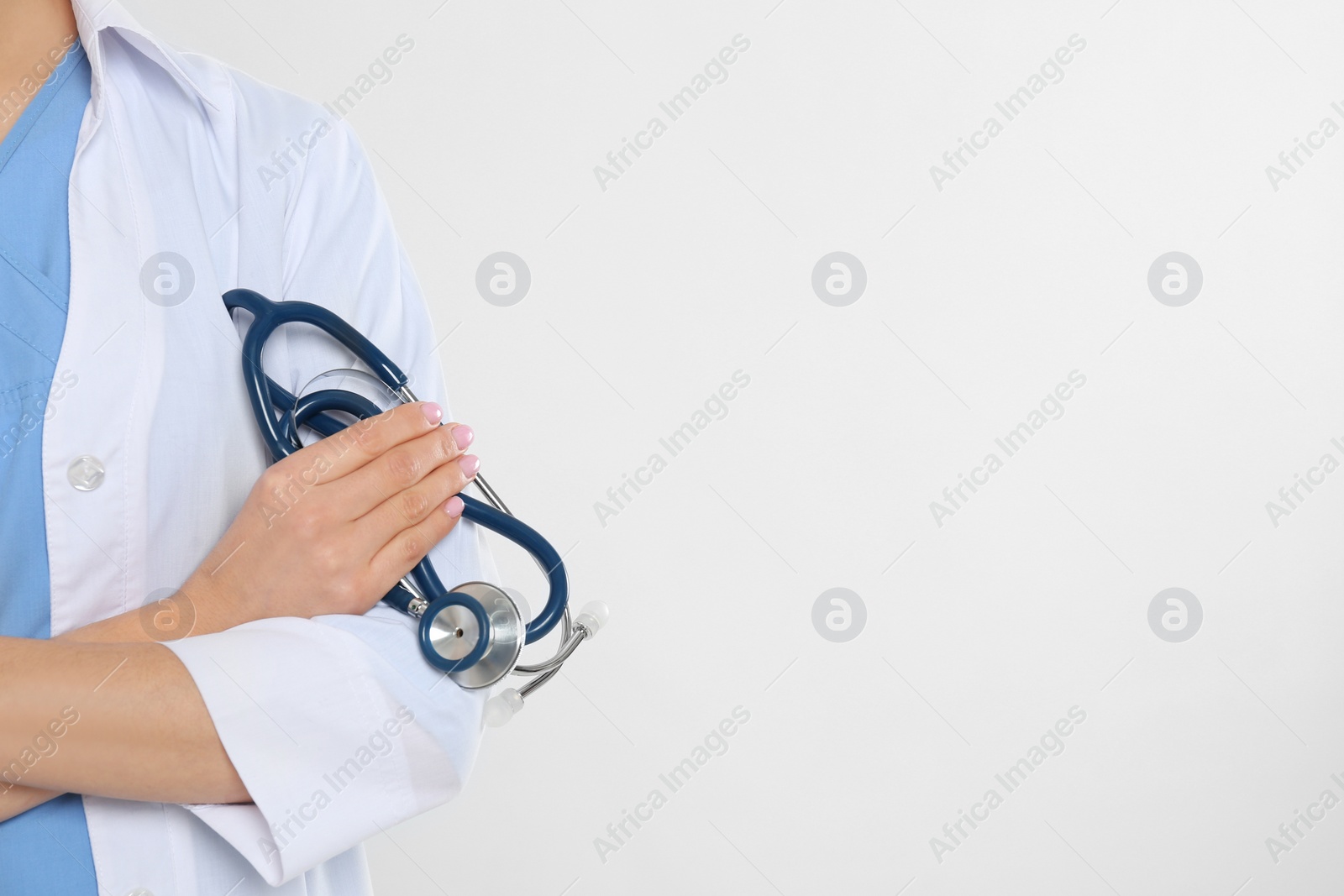 Photo of Young doctor with stethoscope on white background, closeup