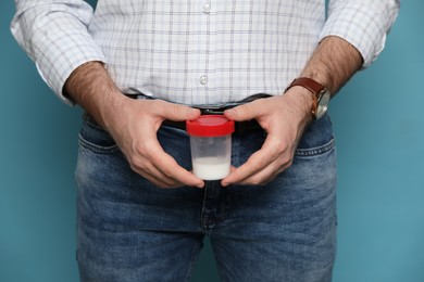 Photo of Donor holding container with sperm on turquoise background, closeup