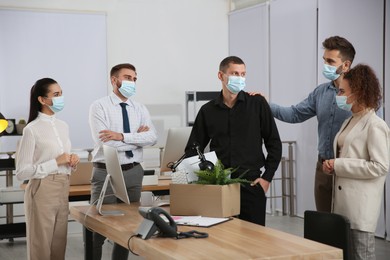Coworkers saying goodbye to dismissed man in office