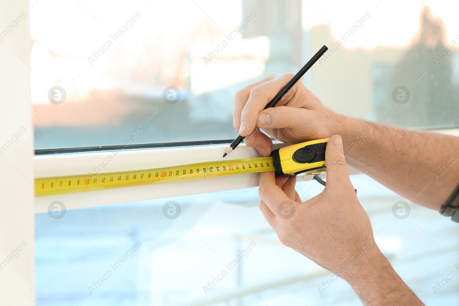 Photo of Service man measuring window for installation indoors, closeup