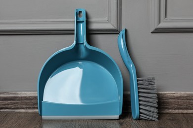 Photo of Plastic whisk broom with dustpan near grey wall indoors