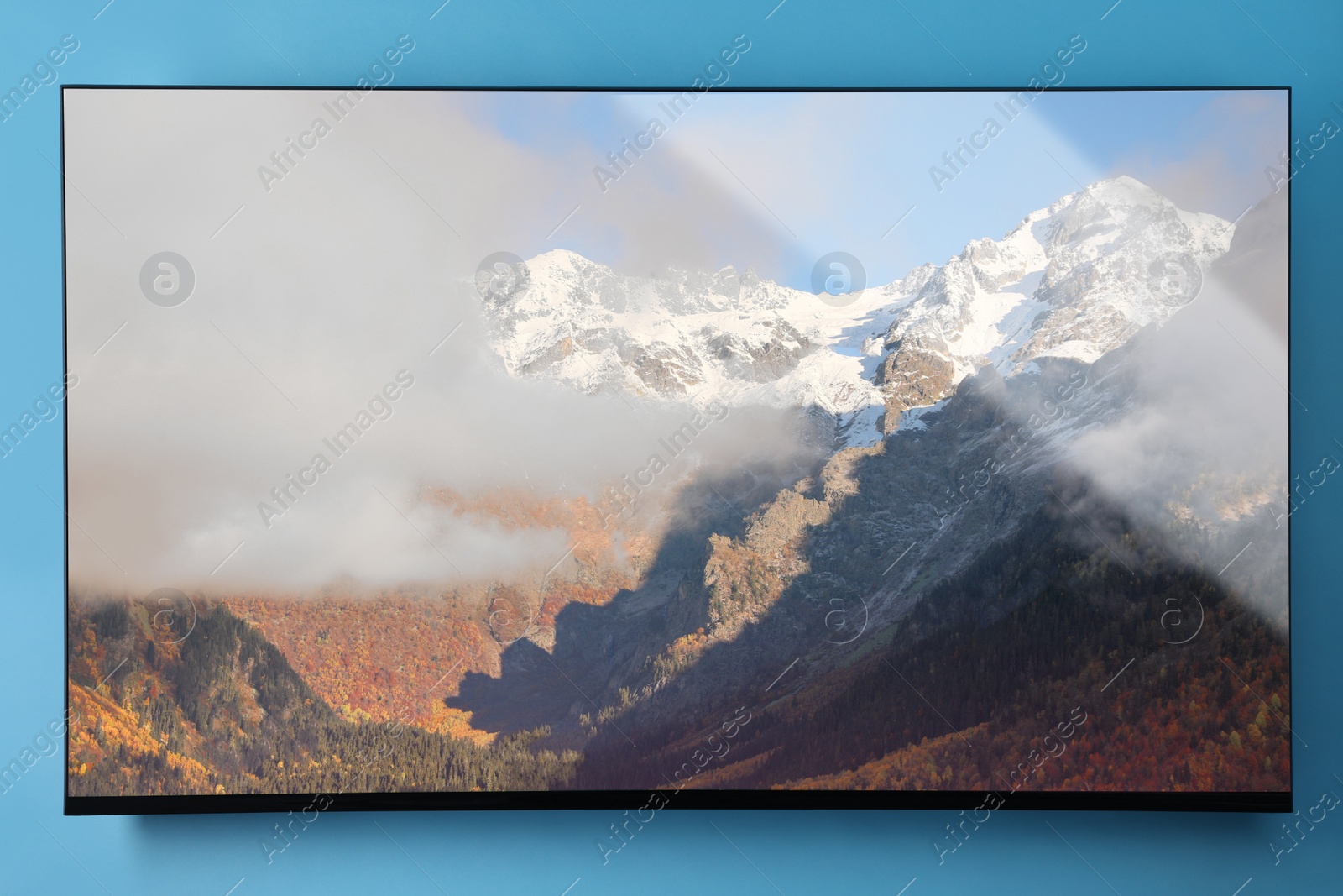 Image of TV screen with mountain landscape on light blue wall