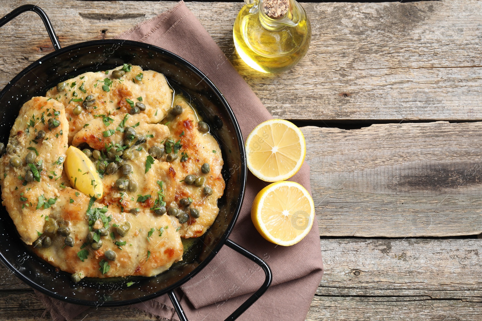 Photo of Delicious chicken piccata with herbs and lemon on wooden table, flat lay. Space for text