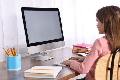 Photo of E-learning. Girl using computer during online lesson at table indoors