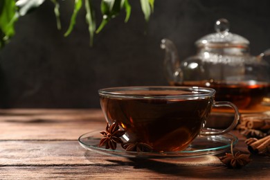 Photo of Aromatic tea with anise stars on wooden table. Space for text