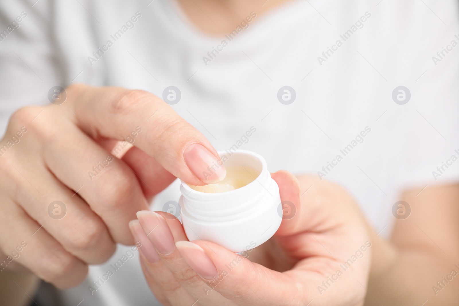 Photo of Woman taking cosmetic petrolatum from jar, closeup