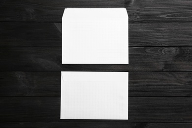 Photo of White paper envelopes on black wooden background, flat lay