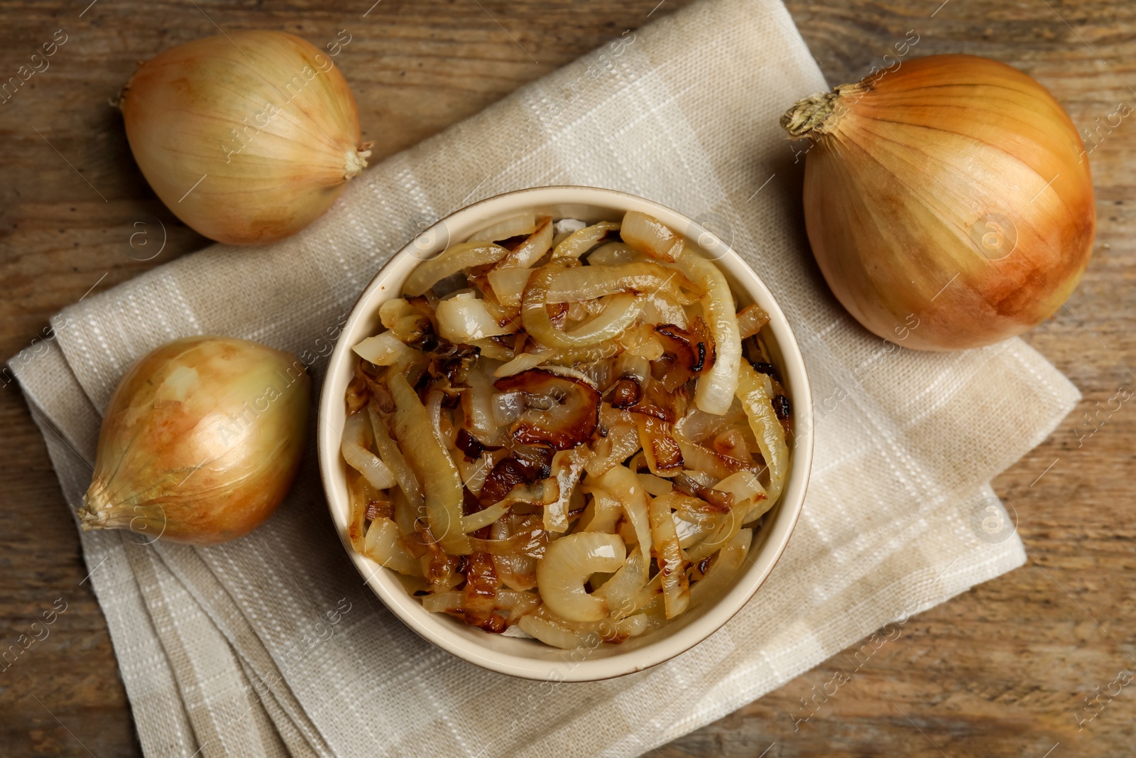 Photo of Tasty fried onion on wooden table, flat lay
