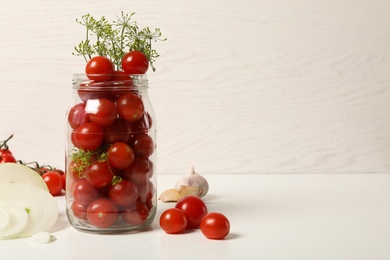 Photo of Pickling jar with fresh tomatoes on white table. Space for text