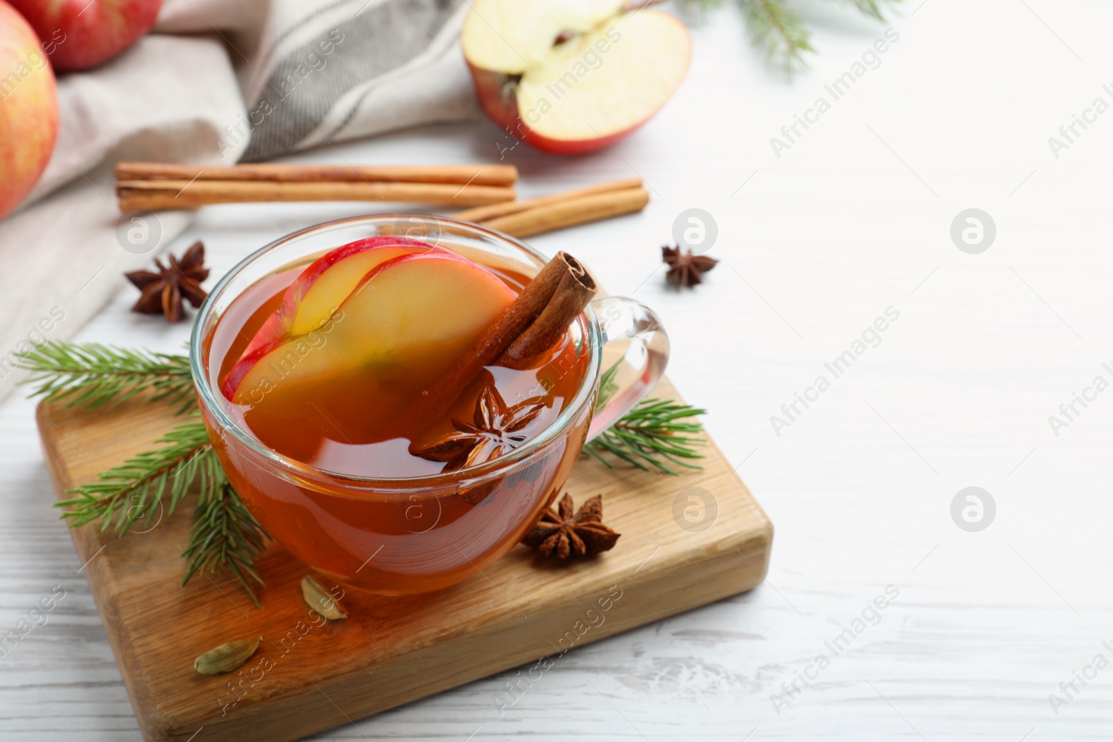 Photo of Aromatic hot mulled cider on white wooden table. Space for text