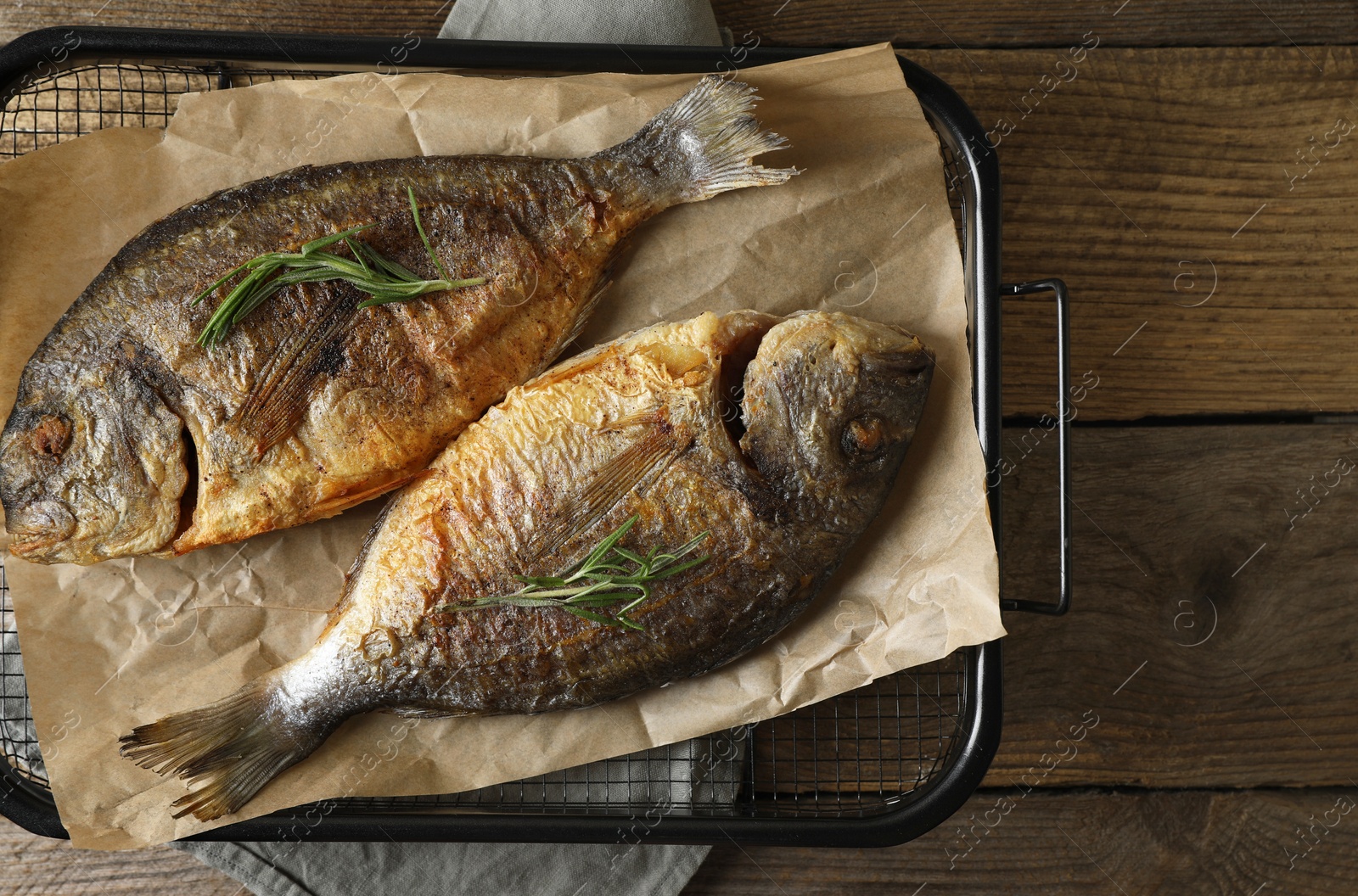 Photo of Delicious dorado fish with rosemary on wooden table, top view