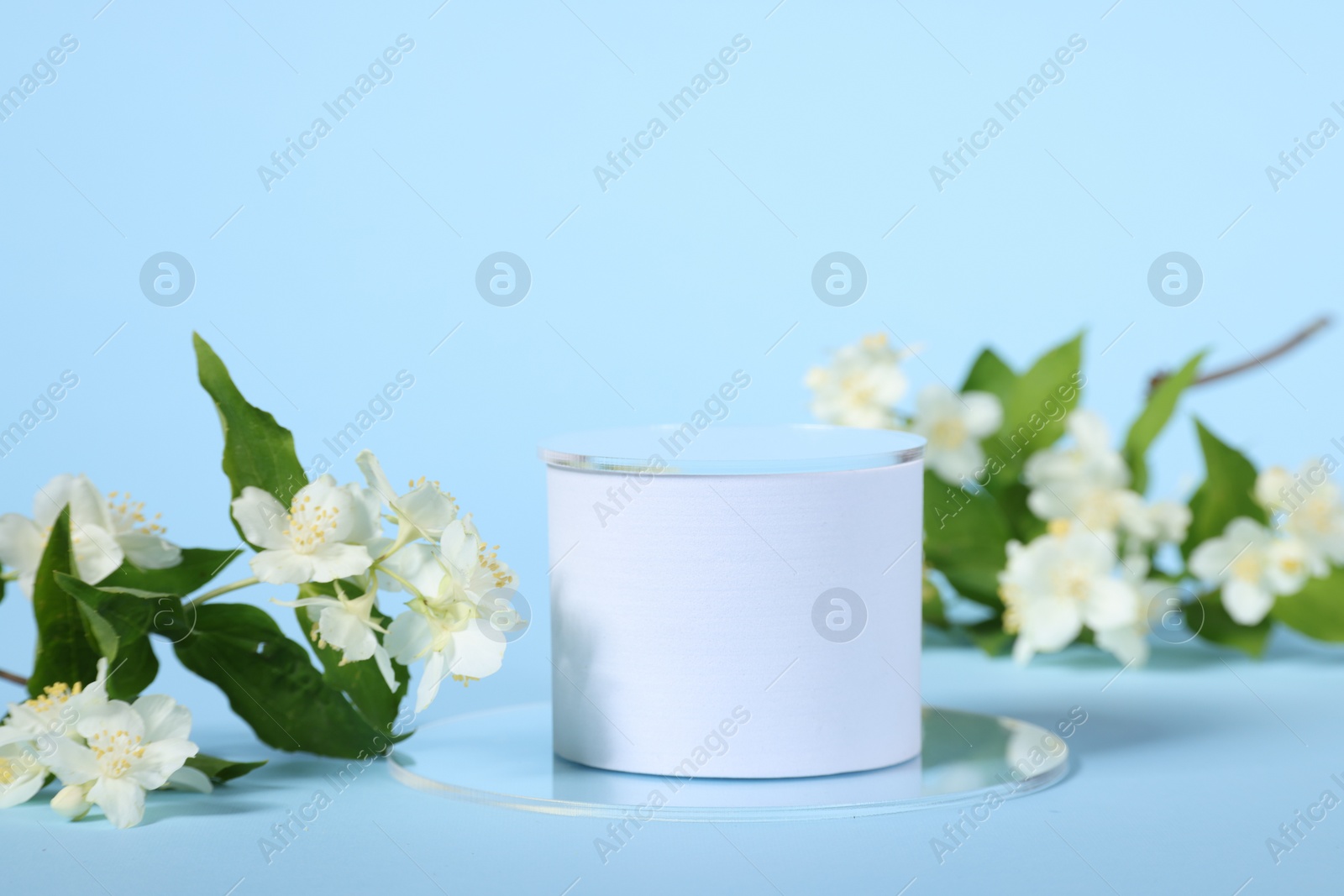 Photo of Presentation of product. White podium and beautiful jasmine flowers on light blue background, space for text