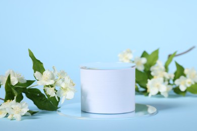 Photo of Presentation of product. White podium and beautiful jasmine flowers on light blue background, space for text