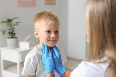 Endocrinologist examining boy's thyroid gland at hospital