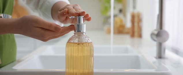 Image of Woman applying liquid soap on hand indoors, closeup. Banner design