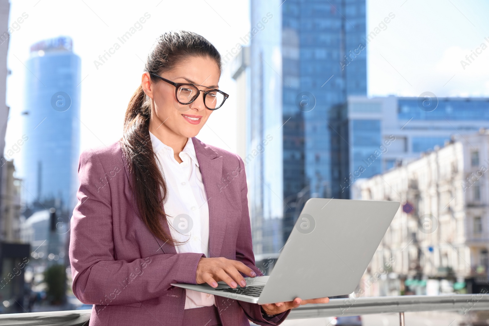 Photo of Beautiful businesswoman with laptop on city street