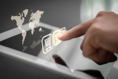 Image of Woman using tablet for online purchases on gray background, closeup. Illustration of world map and shopping cart icons above device screen