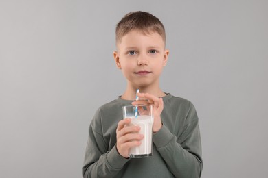 Photo of Cute boy with glass of fresh milk on light grey background