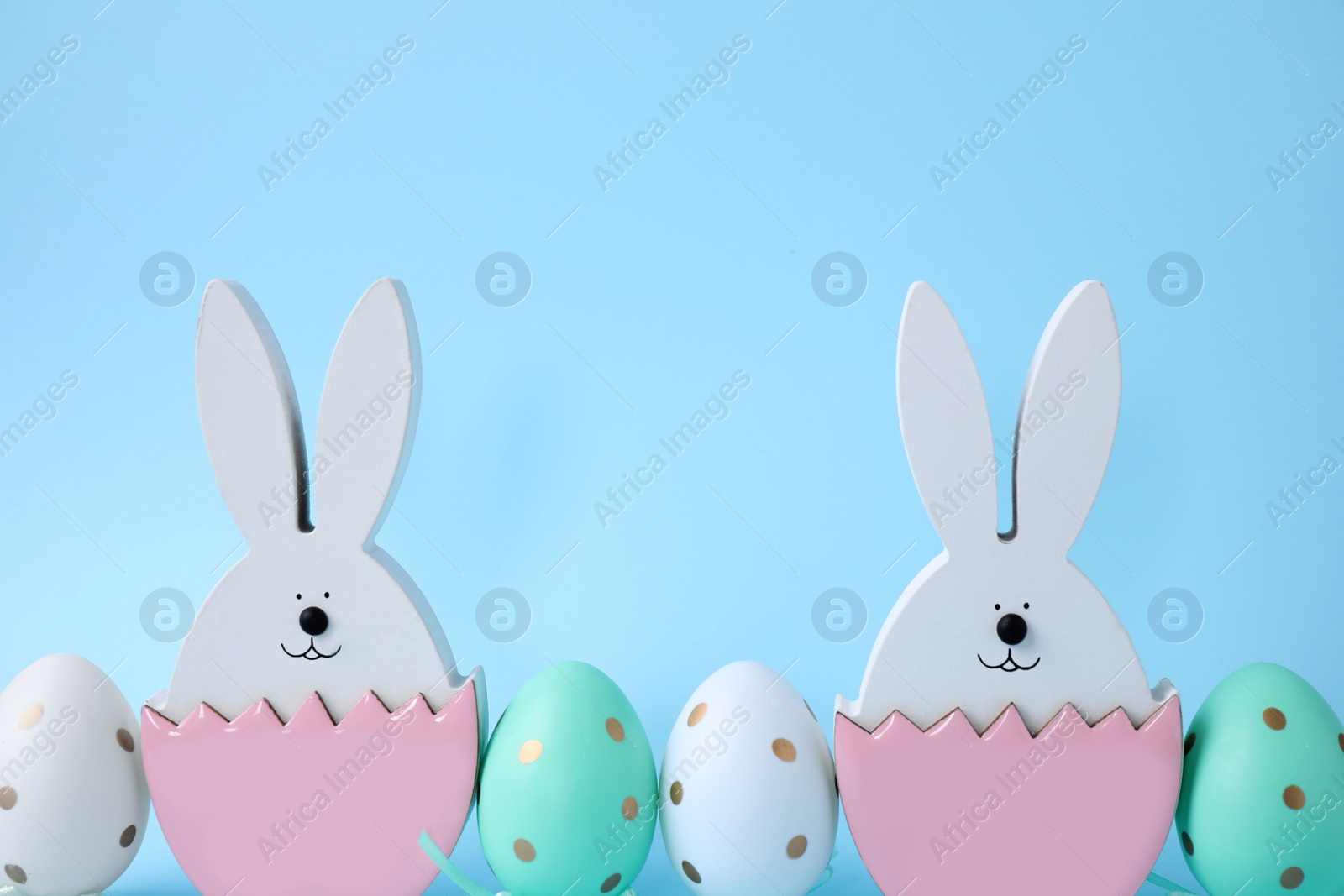 Photo of Easter bunnies and painted eggs on light blue background