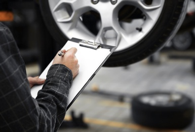Photo of Mechanic with clipboard at tire service, closeup