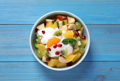 Delicious fruit salad on light blue wooden table, top view