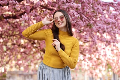 Beautiful woman in sunglasses near blossoming tree on spring day