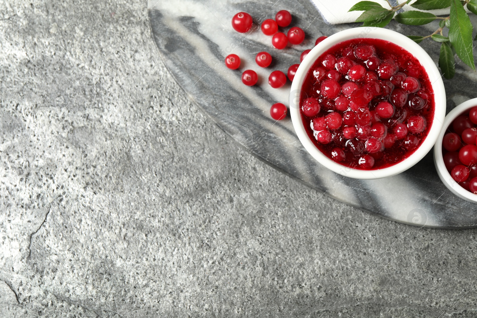 Photo of Flat lay composition with cranberry sauce and fresh berries on grey table, space for text