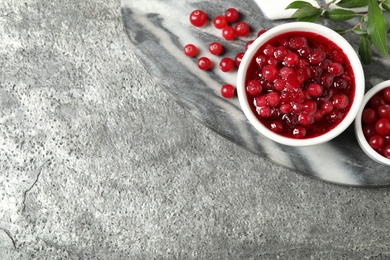 Flat lay composition with cranberry sauce and fresh berries on grey table, space for text