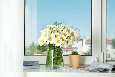 Photo of Vase with beautiful chamomile flowers on windowsill