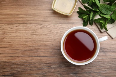 Photo of Cup of hot aromatic tea with mint and honey on wooden table, flat lay. Space for text