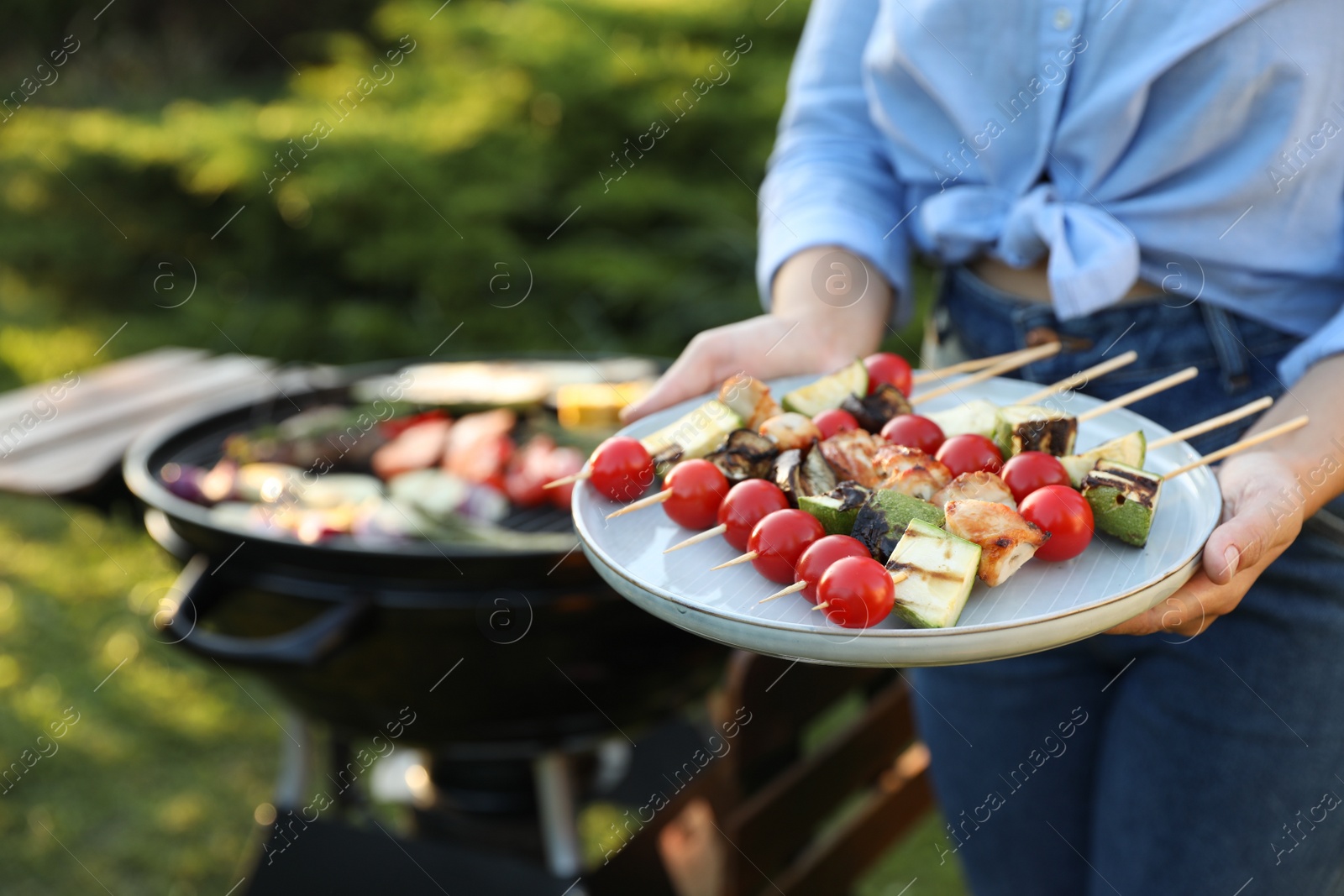 Photo of Woman with delicious grilled vegetables near barbecue grill outdoors, closeup. Space for text