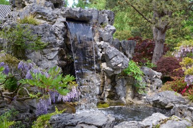 Photo of Beautiful view of waterfall, rocks and plants outdoors