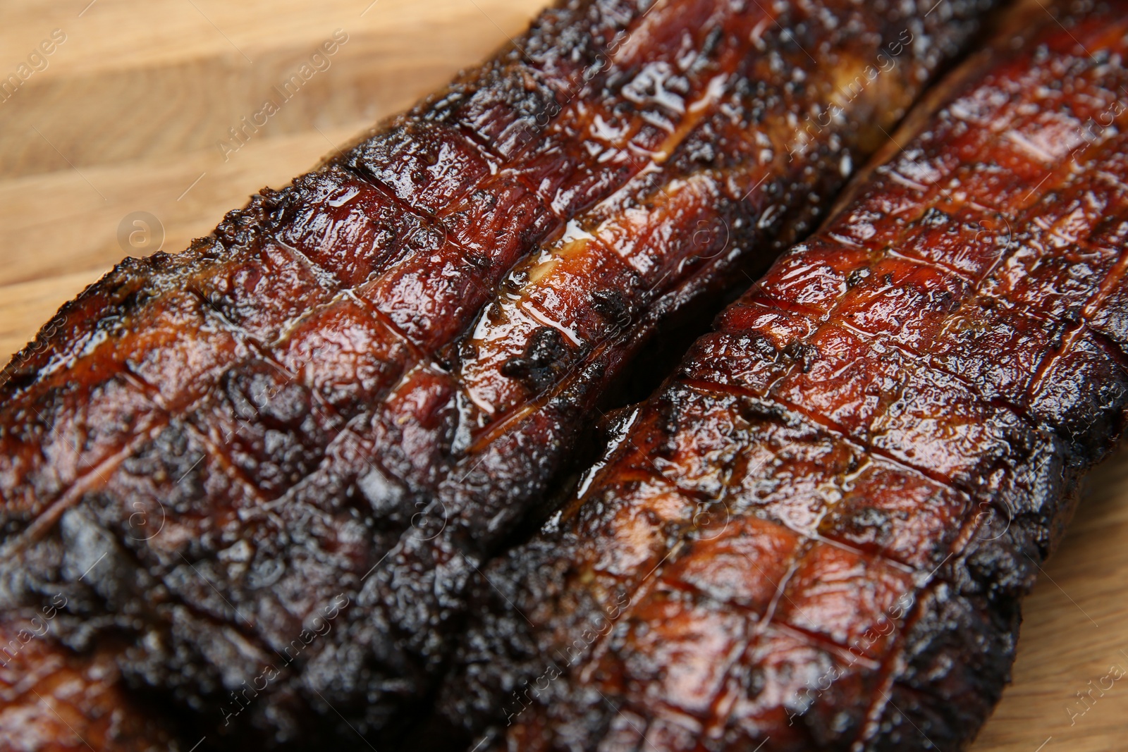Photo of Tasty grilled pork ribs on wooden board, closeup