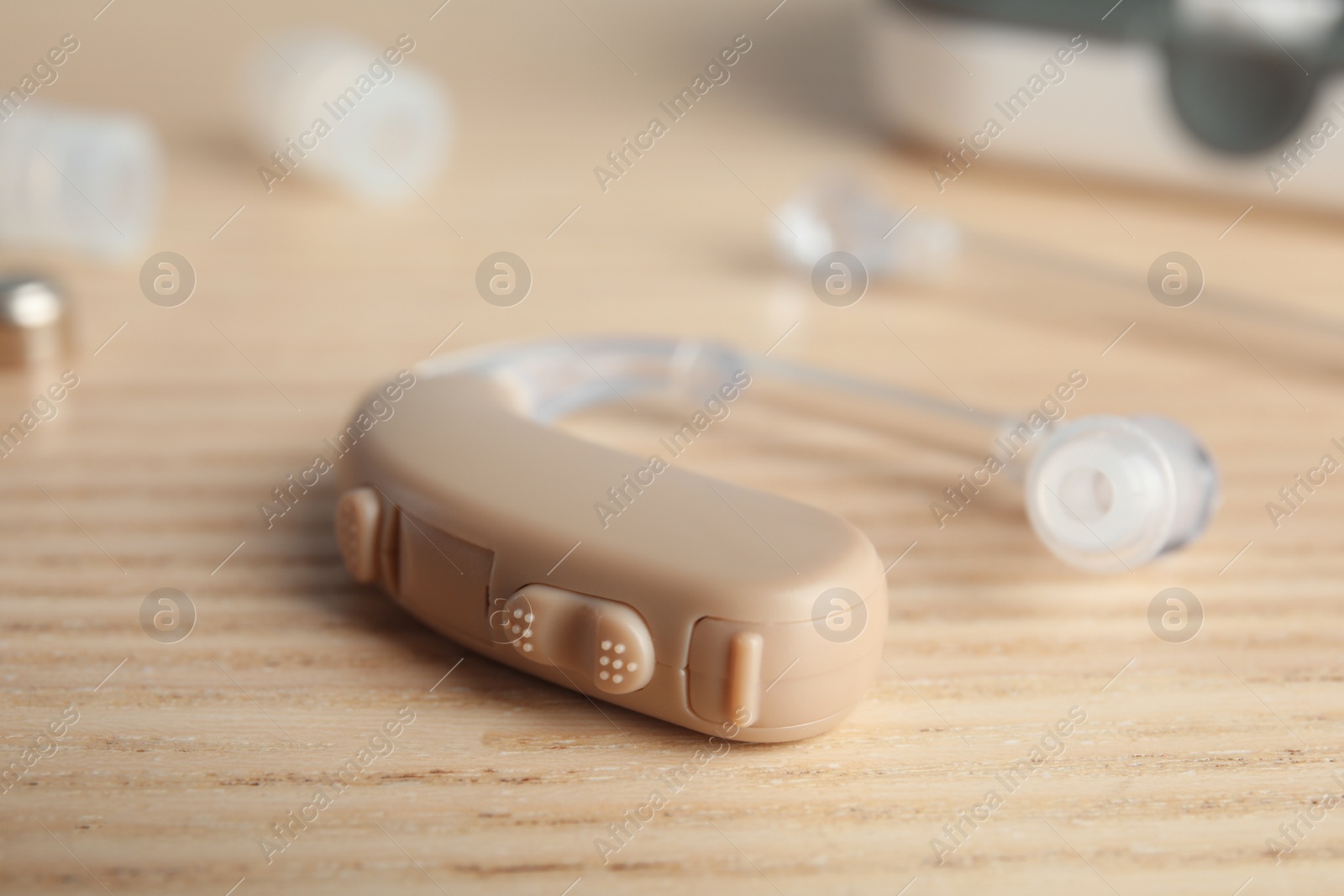 Photo of Hearing aid on wooden table, closeup. Medical device