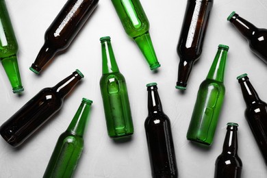 Glass bottles of beer on white background, flat lay