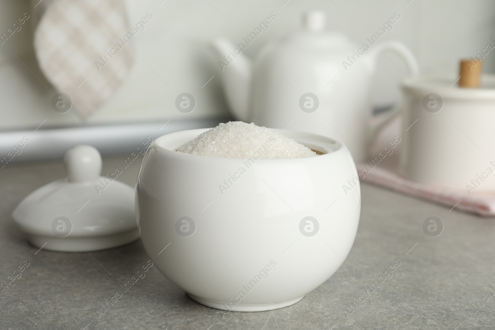 Photo of Ceramic bowl with white sugar on grey table