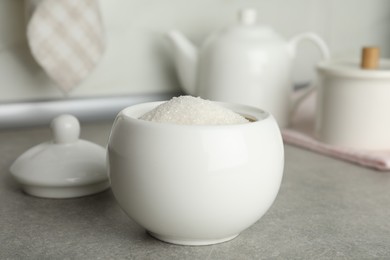 Photo of Ceramic bowl with white sugar on grey table