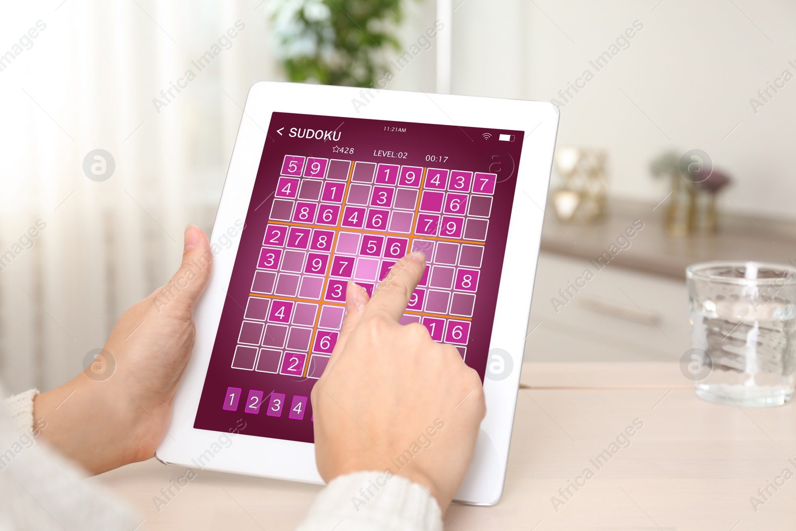 Image of Woman playing sudoku game on tablet indoors, closeup