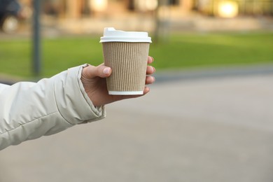 Photo of Woman holding paper takeaway cup outdoors, closeup with space for text. Coffee to go