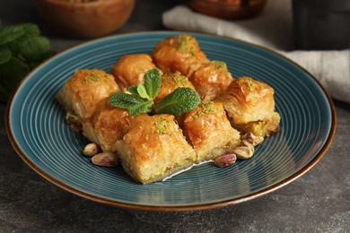 Delicious baklava with pistachio nuts and mint on grey table