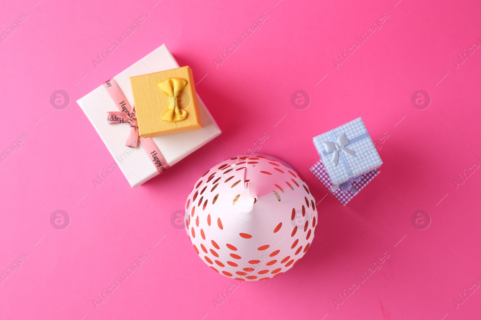 Photo of Party hat and gift boxes on pink background, flat lay