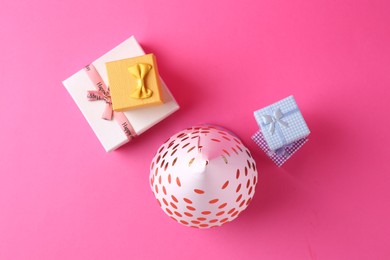 Party hat and gift boxes on pink background, flat lay